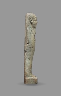 Ushabti, Mummy-shaped figurine standing on a base, back supported by a flat pillar. Arms crossed on