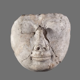 Mummy mask, round face modeled in stucco with large eyes, a wide nose, a mouth in a slight