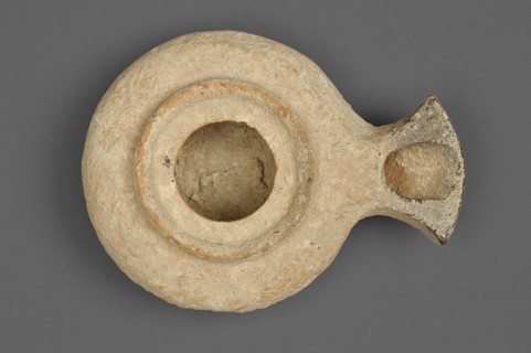 Herodian oil lamp, a small clay lamp with a slightly flattened circular container and a fan-shaped