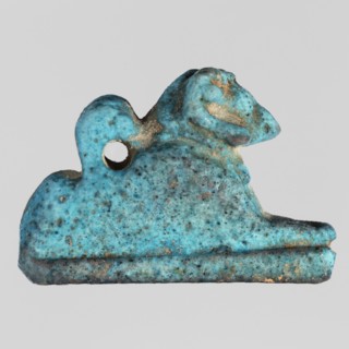 Amulet — ram. Figurine of a ram lying on a flat base, with a loop for hanging on its back.
