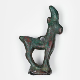 Figurine of an ibex standing on a base in the form of a hollow prism, with two pairs of holes on