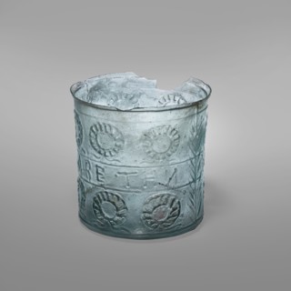 Glass with a wreath motif, Greek inscriptions. Transparent bluish-green glass decorative vessel,