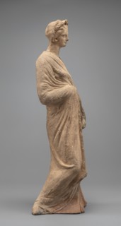 Female figurine, standing woman dressed in a long robe, slightly pleated and belted high under the