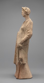 Female figurine: standing woman dressed in a long robe, slightly pleated and belted high under the