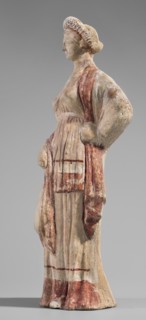 Figurine of a maenad. A young woman standing in a wreath tied with a ribbon is dressed in a chiton
