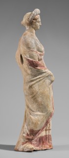 Figurine of a maenad. A young woman standing in a wreath tied with a ribbon is dressed in a chiton