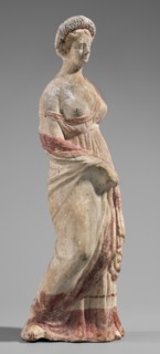 Figurine of a maenad. A young woman standing in a wreath tied with a ribbon is dressed in a chiton