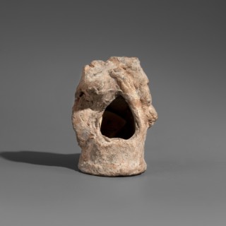 Figurine of a boy. The figurine depicts a youth sitting on a cylindrical base in a relaxed pose.