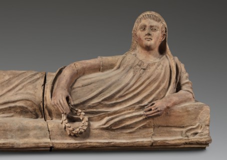 Sarcophagus lid;, The deceased is shown in a semi-reclining position, resting his left forearm on a