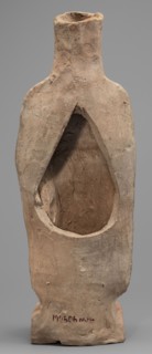 Figurine of a woman standing on a rectangular base. The woman is dressed in a finely pleated chiton