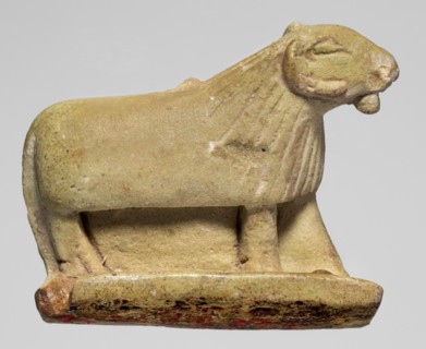 Amulet in the shape of a ram standing on a stand with curled horns and a short beard; the fur