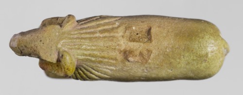 Amulet in the shape of a ram standing on a stand with curled horns and a short beard. The fur
