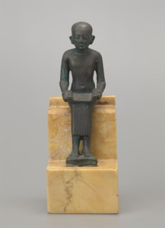 Figurine of Imhotep; seated male figure holding an unrolled papyrus on his lap, palms holding the