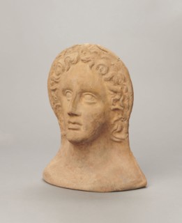 Votive female head;, female head wearing a wreath, from under which lush locks of hair curl down