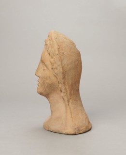 Votive female head, Female head wearing a wreath, from under which lush locks of hair curl down the