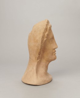 Votive female head, Female head wearing a wreath, from under which lush locks of hair curl down the