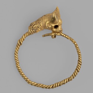 Earring decorated with a bull's head. Earring with a round ring twisted from two wires, pointed at