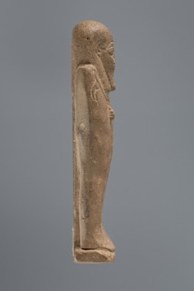 Ushabti, mummy-shaped figurine, standing on a base with a pilaster at the back. Arms crossed on the