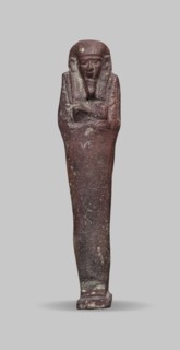 Ushabti, A shabti figurine dressed in a shroud stands on a base. On the head is a smooth wig