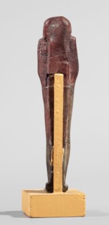 Ushabti, A shabti figurine dressed in a shroud stands on a base. On the head is a smooth wig,