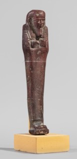 Ushabti, A shabti figurine dressed in a shroud stands on a base. On the head is a smooth wig