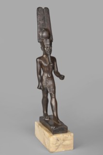 Figurine of the god Amun. Amun mythology. Figurine in a standing posture, wearing a helmet with a