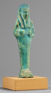 Ushabti; Mummy-shaped funerary figurine standing on a base, supported at the back by a flat
