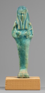 Ushabti. Mummy-shaped funerary figurine, standing on a base, supported at the back by a flat