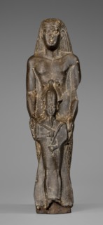 Figurine of a priest with a statuette of the god Osiris. The priest is shown standing, holding in