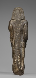 Figurine of a priest with a statuette of the god Osiris. The priest is shown standing, holding in