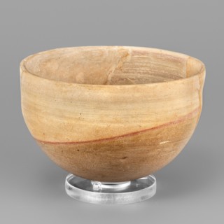 A hemispherical bowl topped with a simple rim, diagonally cut inward. On the outside, below the