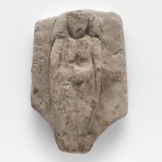Fragment of a figurine of a woman on a bed. Flat figurine of a concubine resting on a plate