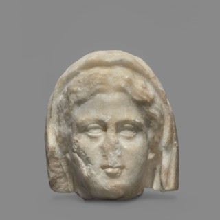 Head of a woman wearing a veil. The face is oval with regular features: rounded chin, small compact