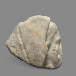 Head of a woman wearing a veil garment. The face is oval, with regular features. The chin is