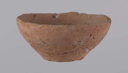 Bowl, probably votive, conical shape with flat bottom. Straight rim, slightly curled toward center.
