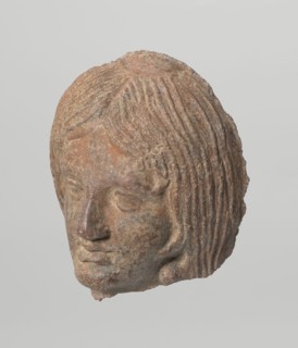 Female votive head with long, straight hair falling to the shoulders. Neck partially preserved.