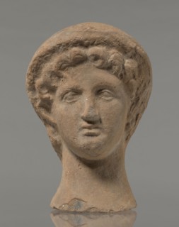 Female votive head, female head in a wreath, slightly tilted to the right shoulder. Under the