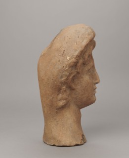 Female votive head. Female head in a wreath, slightly tilted to the right shoulder. Under the