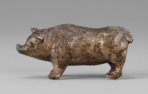 A small bronze figurine of a pig. The animal stands on rather schematically depicted legs ending in