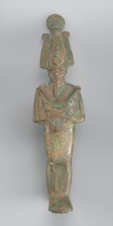 Figurine of Osiris depicted as a mummy-like standing figure wrapped in a shroud. The arms