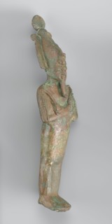 Figurine of Osiris depicted as a mummy-like standing figure wrapped in a shroud. The arms