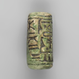 Cylinder seal with pseudo-hieroglyphs. A cylindrical seal with a hole drilled along the cylinder.