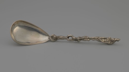 Decorative spoon with a teardrop-shaped, smooth scoop and a handle decorated with a mascaron at the