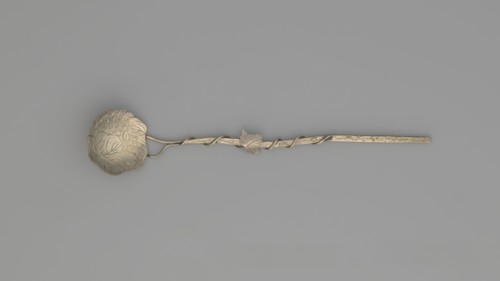 Decorative spoon with a flat round scoop with irregular edges decorated on both sides with engraved