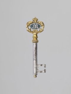 Souvenir key, steel, with a full shank and a simple feather in the form of two square brackets.