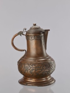 Jug. On a circular, stepped base, the body bulges in the lower part, decorated with a repoussé