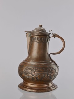 Jug. On a circular, stepped base, the body bulges in the lower part, decorated with a repoussé
