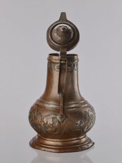 Jug. On a circular, stepped base, the body bulges in the lower part, decorated with a repoussé