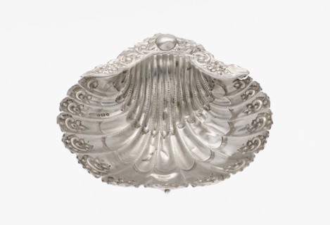 Platter in the form of a full-plastic scallop shell, knotted and ribbed, decorated on the rim with
