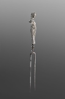 Fork. Two-pronged steel fork with a silver handle shaped as a full-plastic female herm, decorated